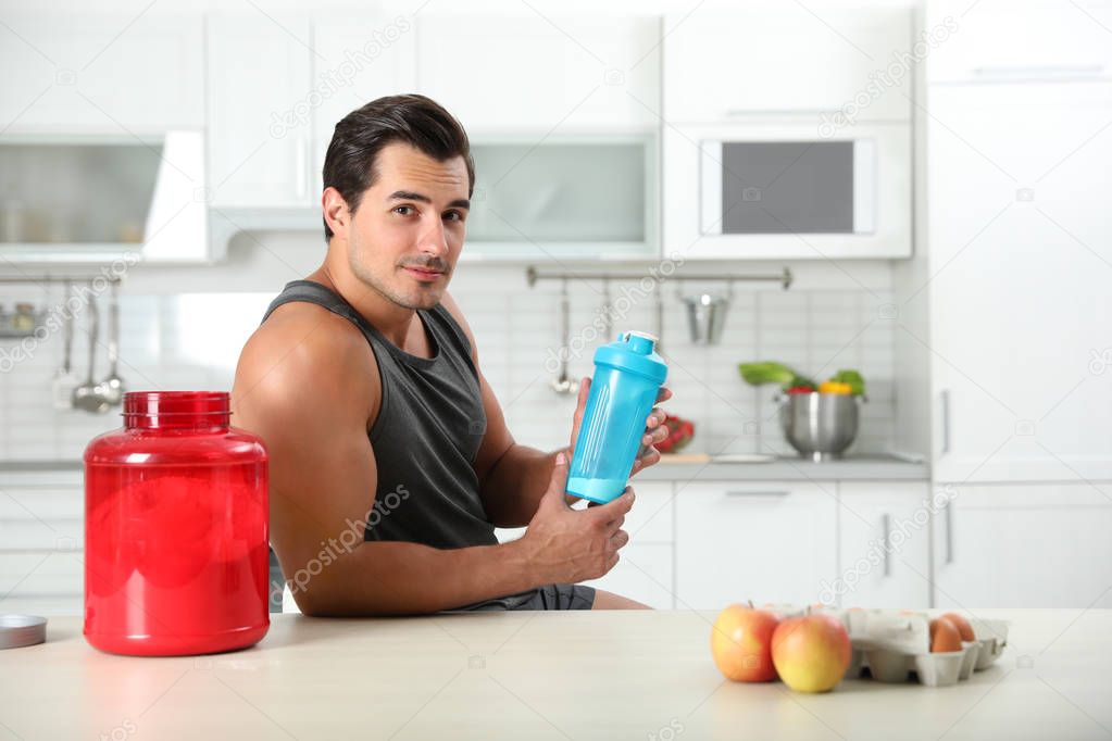 Young athletic man with ingredients for protein shake in kitchen, space for text