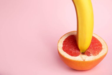 Pembe arka planda taze greyfurt ve muz, metin için alan. Seks kavramı