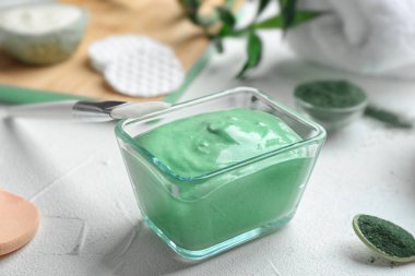 Spirulina yüz maskesi ve beyaz masa üzerinde fırça