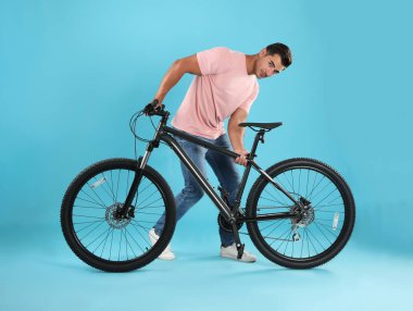 Açık mavi arka plan üzerinde modern bisiklet ile Yakışıklı genç adam