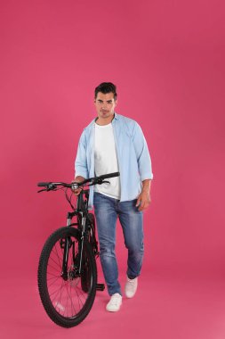 Pembe arka plan üzerinde modern bisiklet ile Yakışıklı genç adam