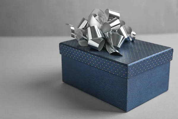 Hermosa caja de regalo con arco en la mesa de luz — Foto de Stock