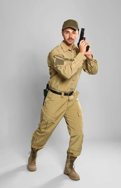 Male security guard in uniform with gun on grey background