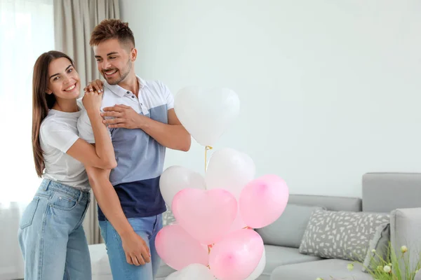 Junges Paar mit Luftballons zu Hause. Feier zum Valentinstag — Stockfoto