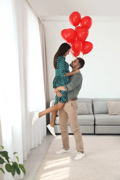 Junges Paar mit Luftballons zu Hause. Feier zum Valentinstag — Stockfoto