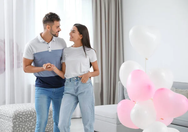 Young couple in living room decorated with air balloons. Celebration of Saint Valentine\'s Day