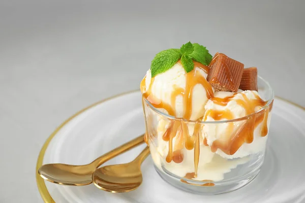 Вкусное мороженое с карамельным соусом, конфеты и мята подается на светло-сером столе — стоковое фото