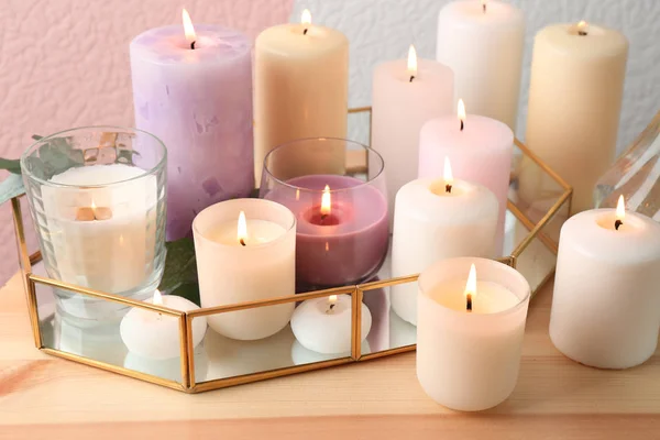 Conjunto de velas encendidas en la mesa contra el fondo de color —  Fotos de Stock