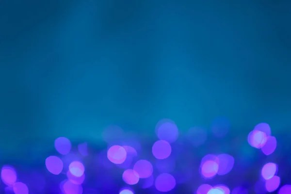 Розмиті фіолетові різдвяні вогні на синьому фоні — стокове фото