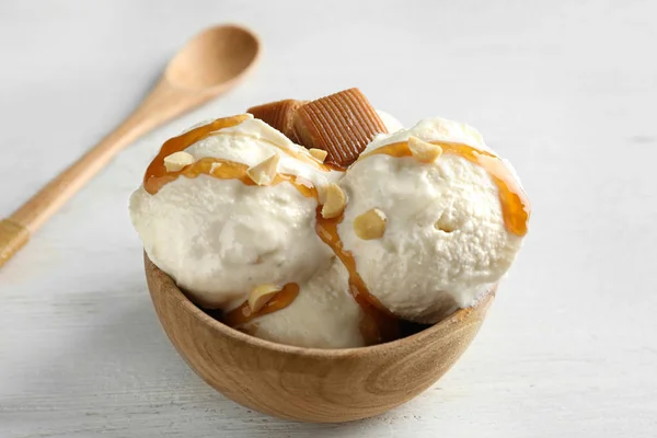 Вкусное мороженое с карамельными конфетками в миске на белом деревянном столе — стоковое фото
