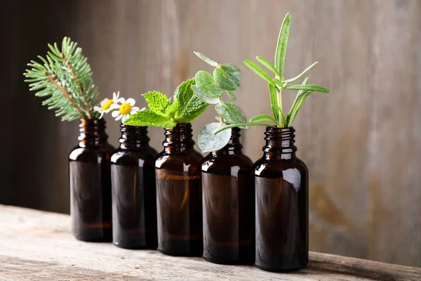 Glasflaskor av olika eteriska oljor med växter på bordet — Stockfoto