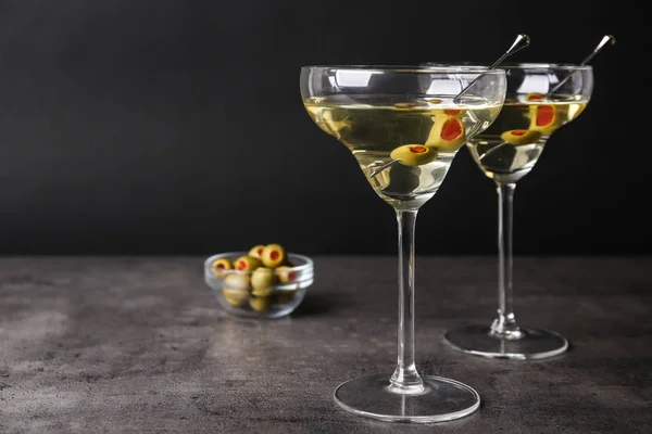 Glas klassisk Dry Martini med Oliver på grått bord mot svart bakgrund. Utrymme för text — Stockfoto