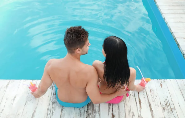 Mujer en bikini con novio cerca de piscina al aire libre. Pareja joven — Foto de Stock