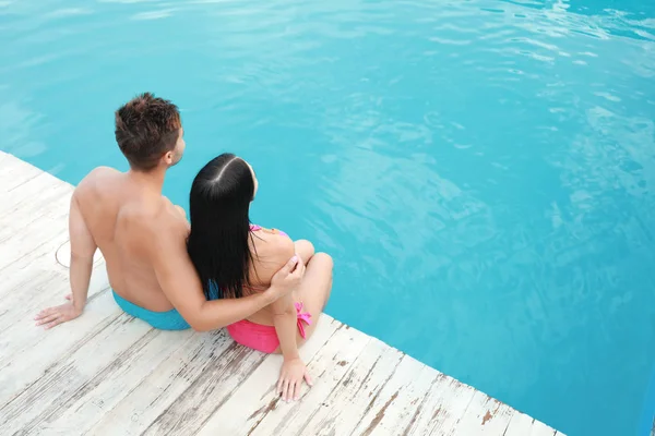 Mujer en bikini con novio cerca de piscina al aire libre. Pareja joven — Foto de Stock