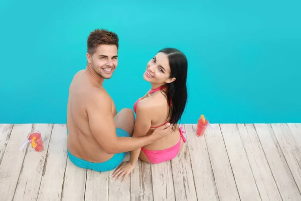 Donna in bikini con fidanzato vicino alla piscina all'aperto. Felice giovane coppia — Foto Stock