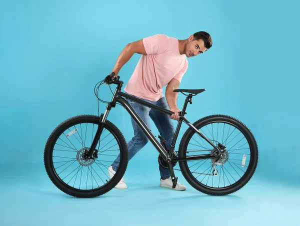 Açık mavi arka plan üzerinde modern bisiklet ile Yakışıklı genç adam