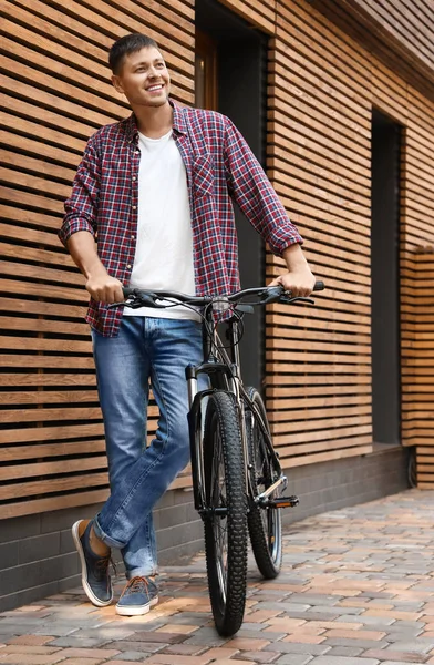 Красивий чоловік з сучасним велосипедом біля будівлі на відкритому повітрі — стокове фото