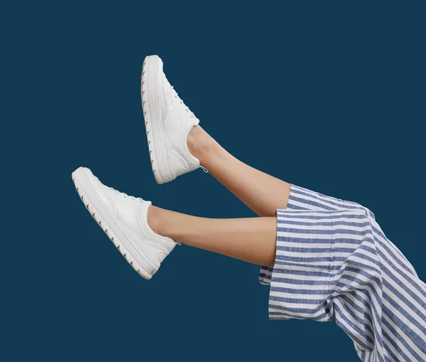 Vrouw in stijlvolle sportschoenen op blauwe achtergrond — Stockfoto