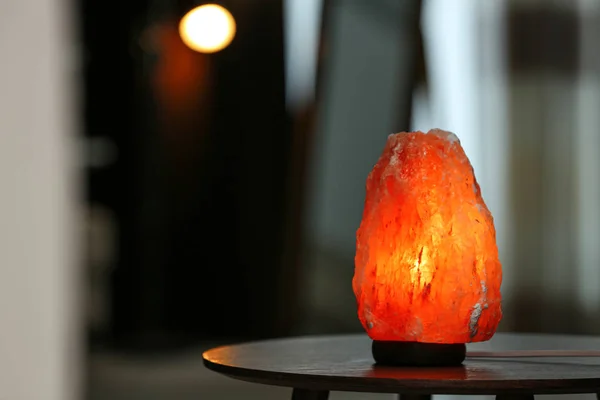 Himalayan salt lamp on table in room. Space for text