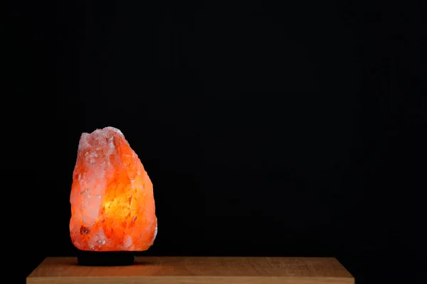 Himalayan salt lamp on table against black background. Space for text — Stock Photo, Image