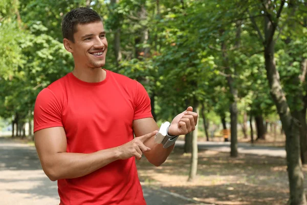 Hombre joven comprobando el pulso con dispositivo médico después del entrenamiento al aire libre — Foto de Stock