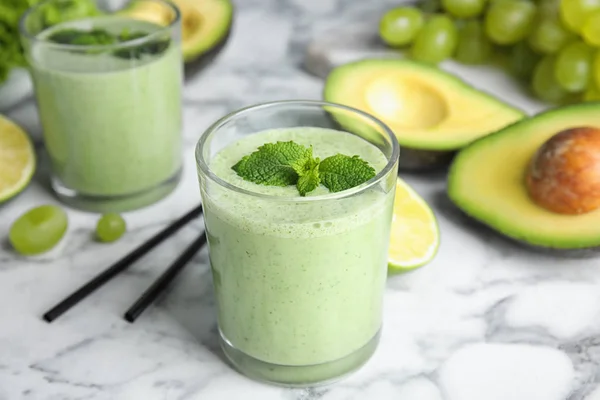 Glazen smakelijke avocado smoothie met munt op marmeren tafel — Stockfoto