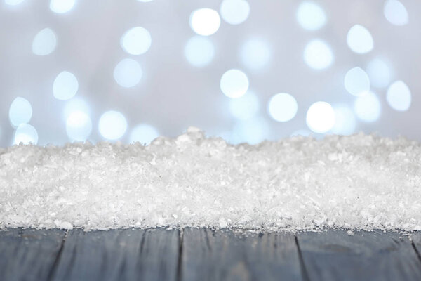 Heap of snow on wooden surface against blurred background. Christmas season