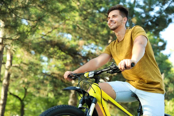 Красивий молодий чоловік з велосипедом в парку, низький кут зору — стокове фото