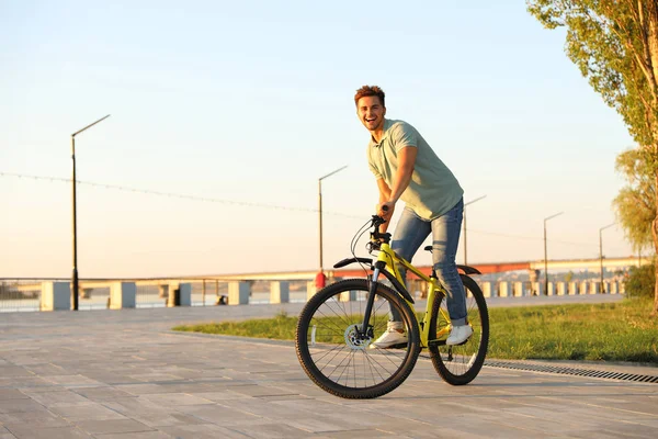 Beau jeune homme à vélo sur le front de mer de la ville — Photo