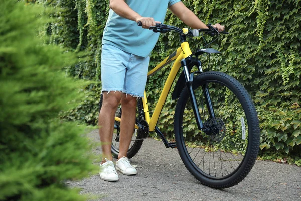 Jeune homme avec vélo près du mur recouvert de lierre vert vignes sur la rue de la ville, gros plan — Photo