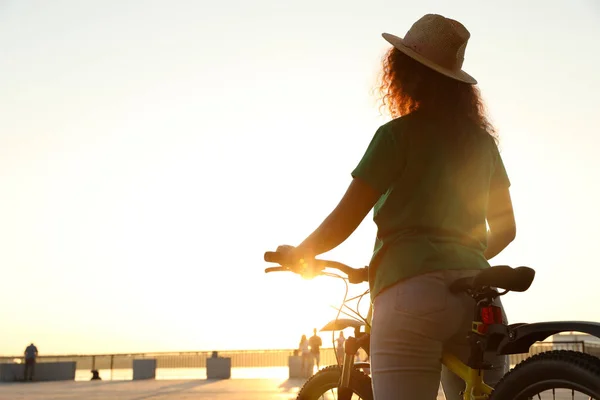 Молоді афро-американської жінки з велосипеда на набережній міста на заході сонця — стокове фото
