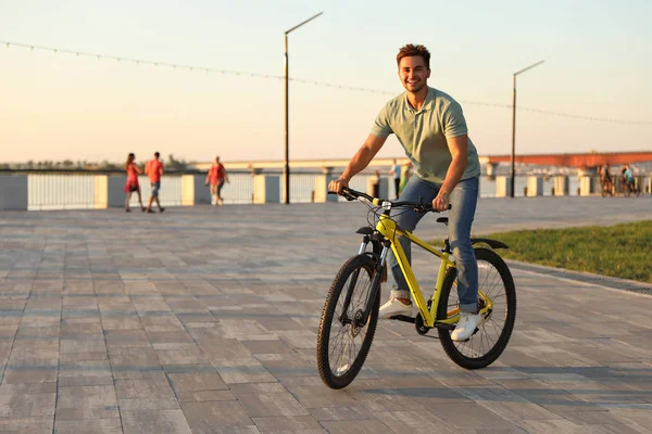 Beau jeune homme à vélo sur le front de mer de la ville — Photo