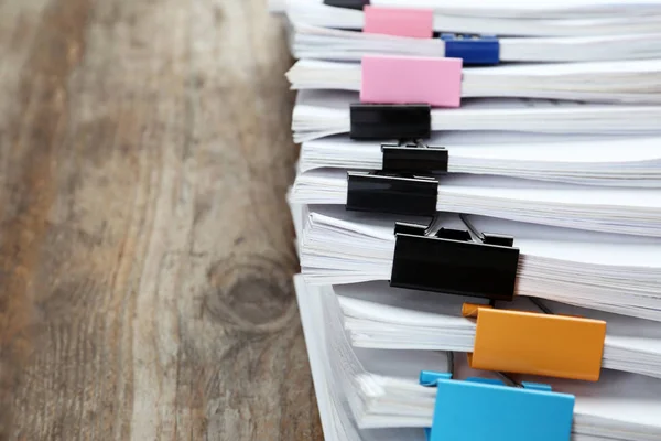 Documents with colorful binder clips on wooden table, closeup
