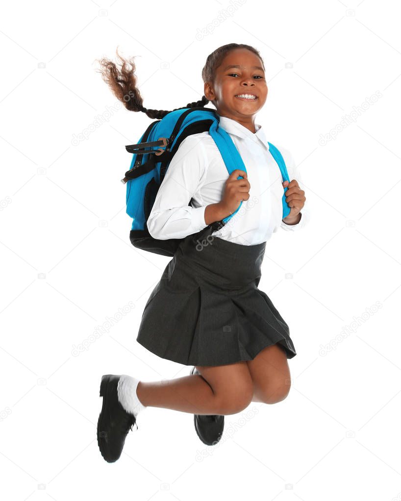 Happy African-American girl in school uniform jumping on white background