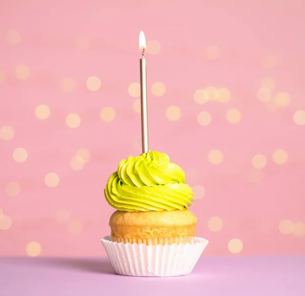 Cupcake di compleanno con candela sul tavolo contro le luci festive — Foto Stock
