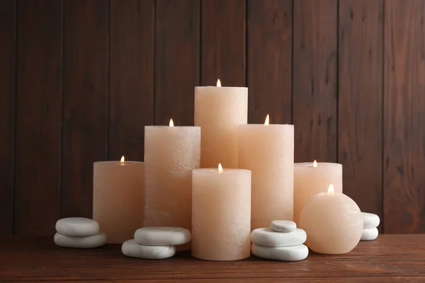 Komposition mit brennenden Kerzen auf Tisch vor hölzernem Hintergrund — Stockfoto