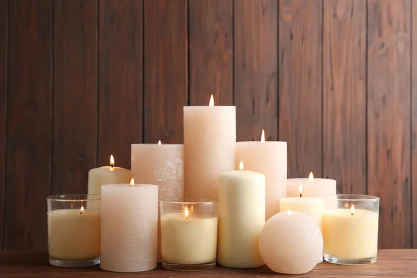 Conjunto de velas em chamas na mesa contra fundo de madeira — Fotografia de Stock
