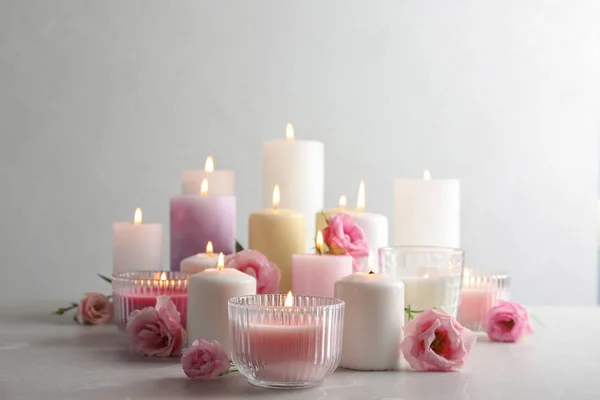 Composition with burning candles on table against light background — Stock Photo, Image