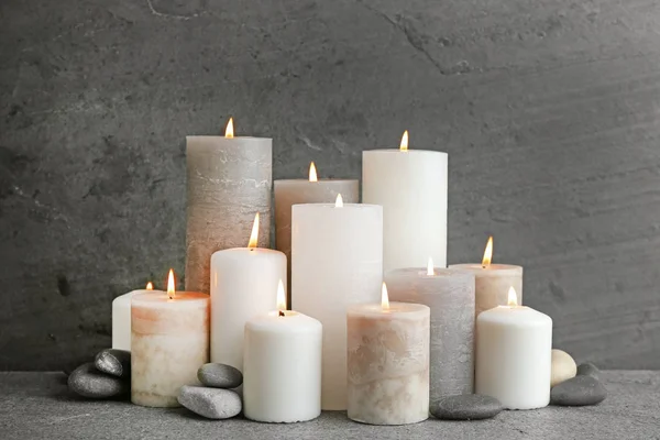 Komposition mit brennenden Kerzen auf Tisch vor grauem Hintergrund — Stockfoto