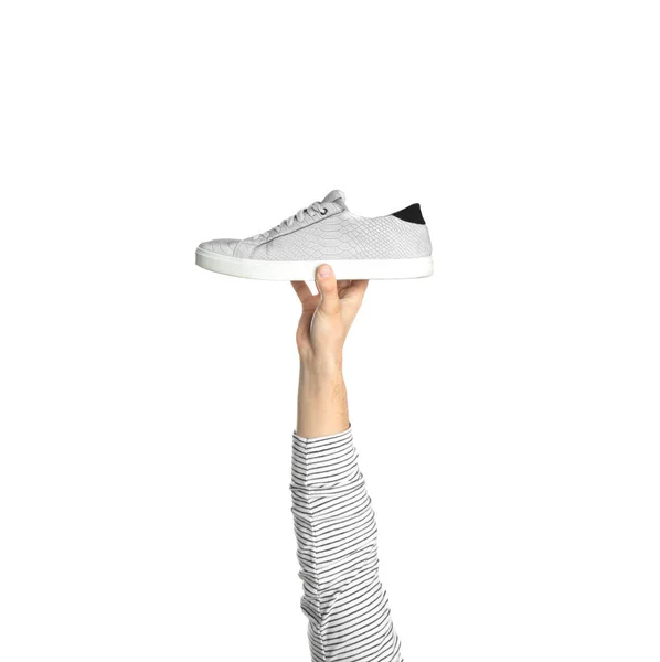 Ung man håller bekväm sko på vit bakgrund, närbild — Stockfoto