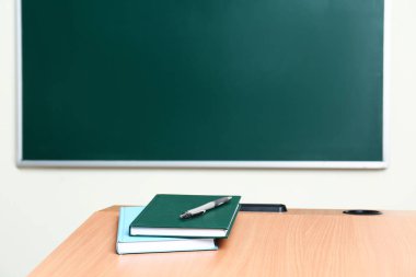 Sınıfta tebeşir tahtası yakınında kırtasiye ile ahşap okul sırası