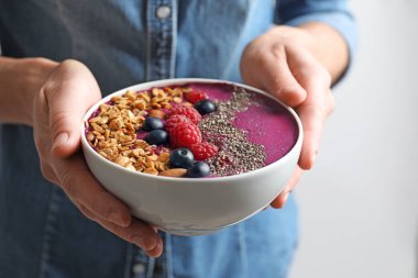 Kadın granola ve çilek ile acai smoothie kase tutan, closeup