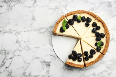 Beyaz mermer arka plan üzerinde böğürtlen ile dilimlenmiş lezzetli cheesecake, üst görünümü. Metin için alan