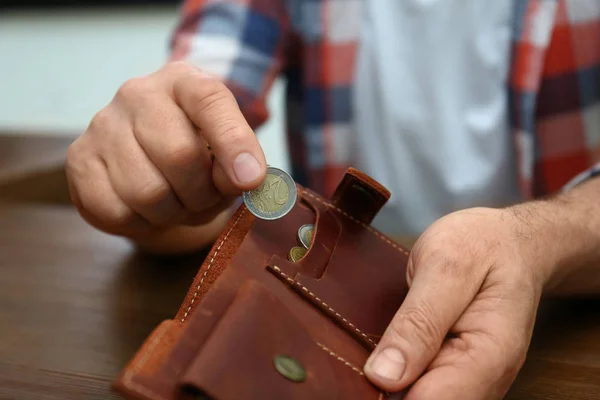 Hombre mayor poniendo moneda en el bolso en la mesa, primer plano — Foto de Stock