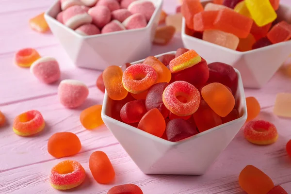 粉红色木桌上的美味果冻糖果碗，特写 — 图库照片