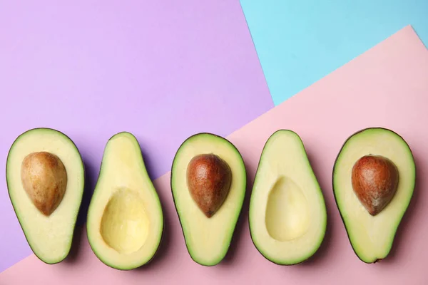 Geschnitten frische reife Avocados auf farbigem Hintergrund, flache Lage mit Platz für Text — Stockfoto