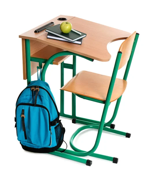Деревянный школьный стол с канцелярскими принадлежностями, рюкзак и яблоко на белом фоне — стоковое фото