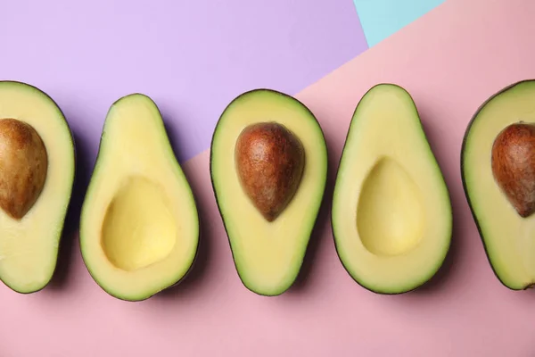 Snijd verse rijpe avocado's op kleur achtergrond, platte lay — Stockfoto