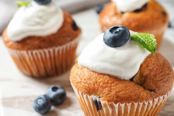 Muffin saporiti, panna e mirtilli in tavola, primo piano — Foto Stock