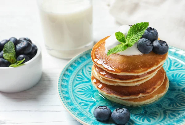 Plate of tasty pancakes with blueberries, sauce and mint on white wooden table, closeup — Stock Photo, Image